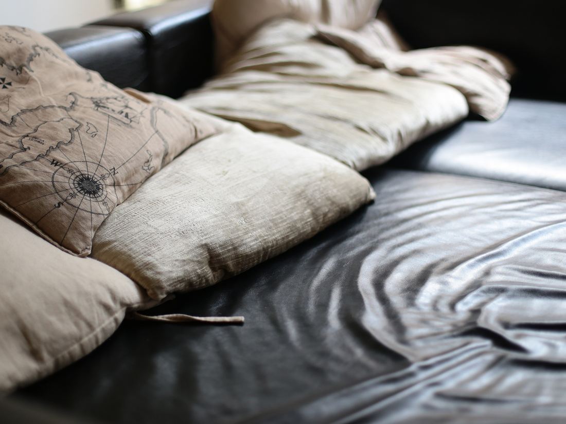 A dark leather sofa with linen cushions