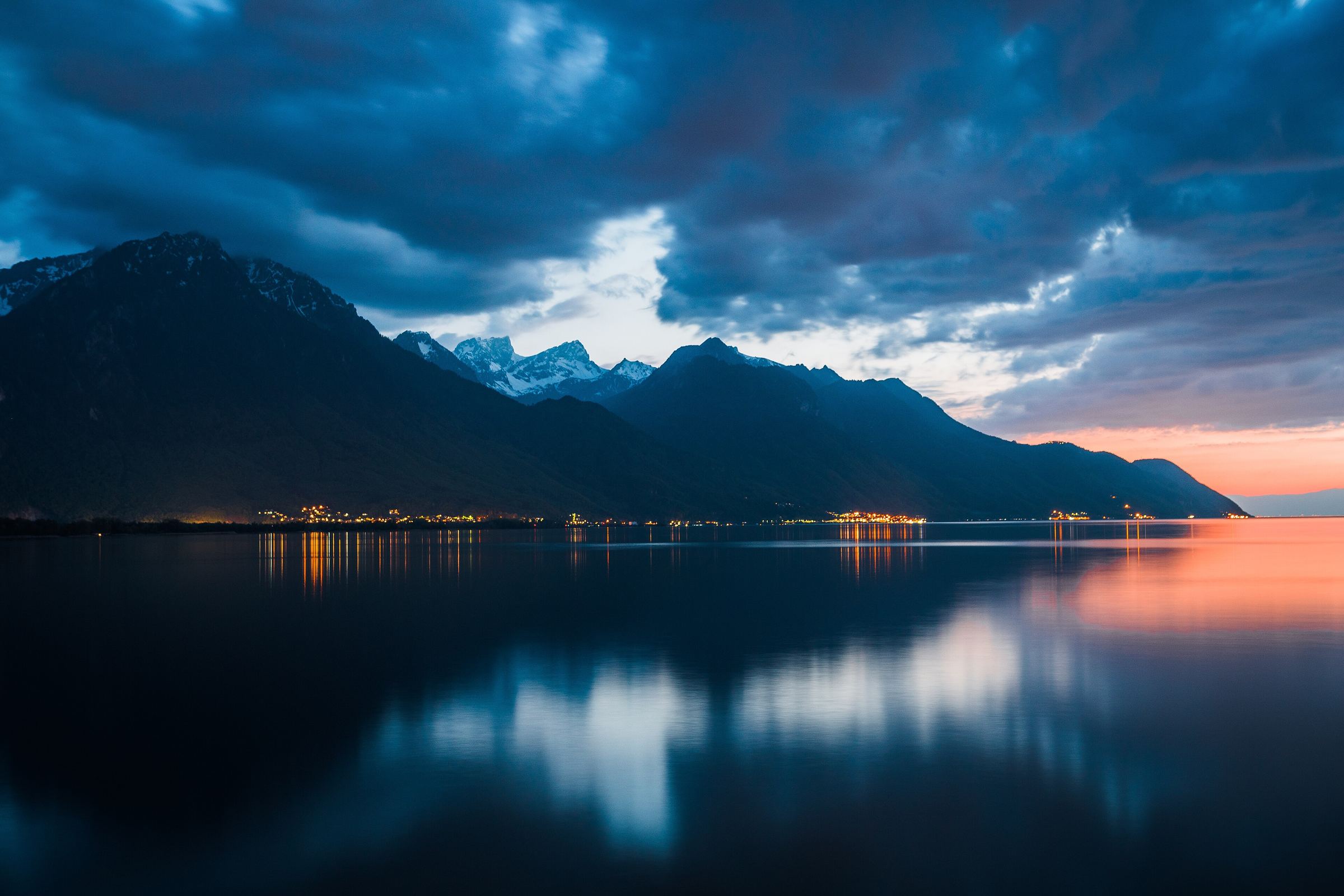 Lake Geneva at the blue hour, with the Alps and the lights of the shore reflected in the water